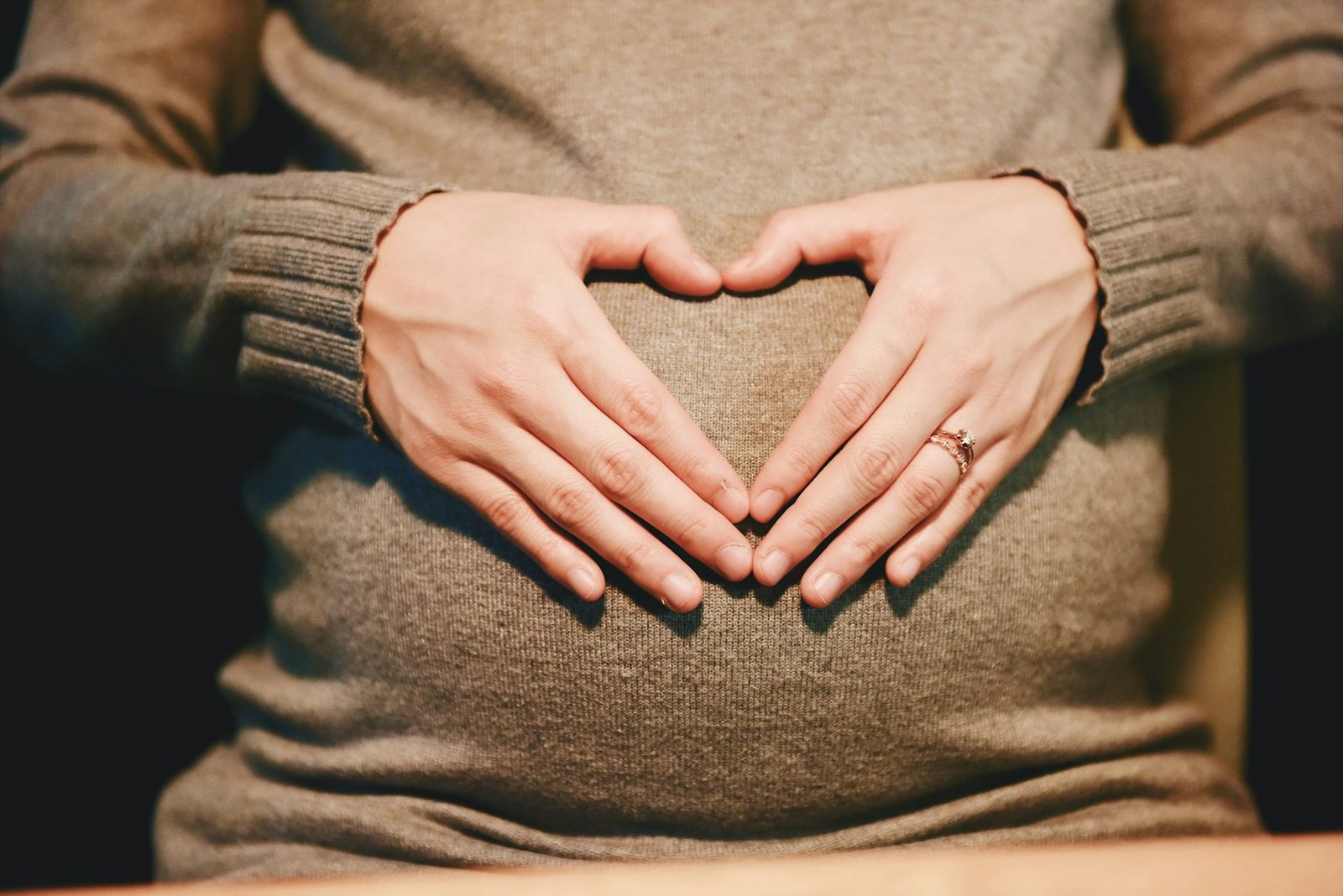 Gravid kvinne former hjerte med hendene over magen